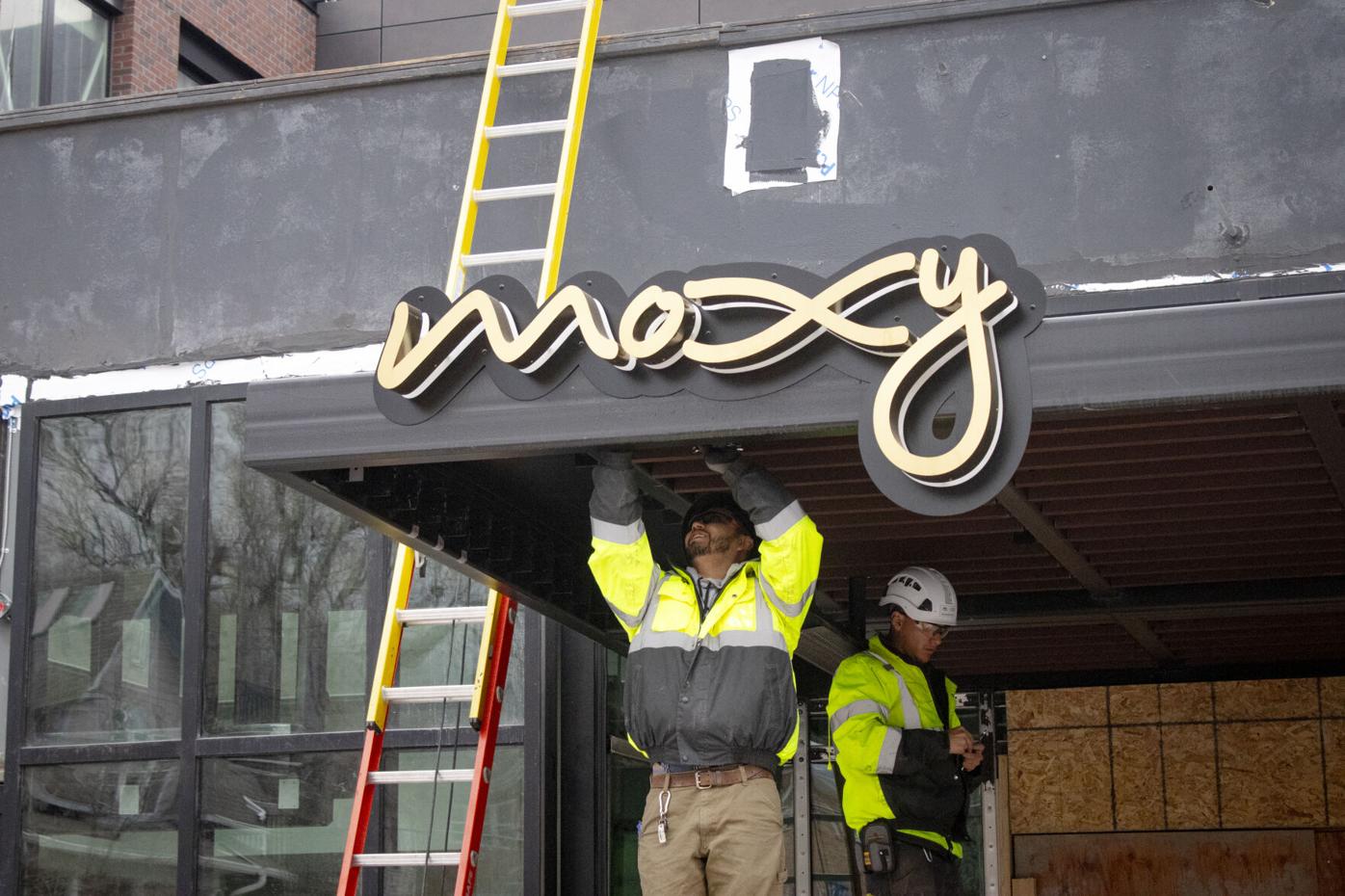 Construction worker adjusting Moxy Boulder sign