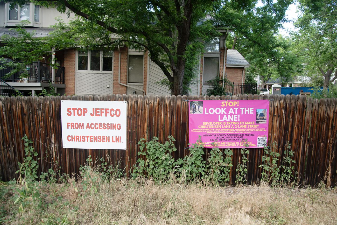 Neighbors hang signs in opposition to a plan to open Littleton, Colo.'s Christensen Lane
